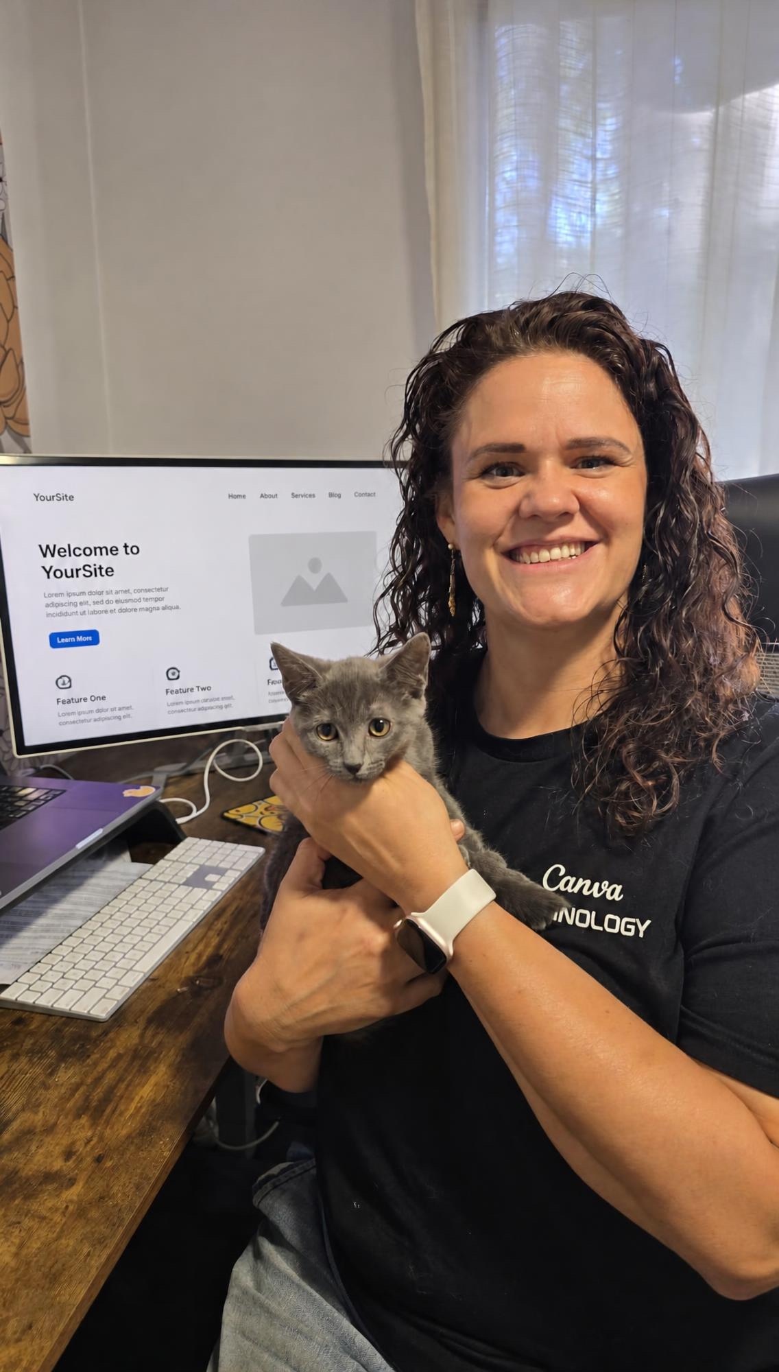 Cheryl at her desk holding a grey foster kitten