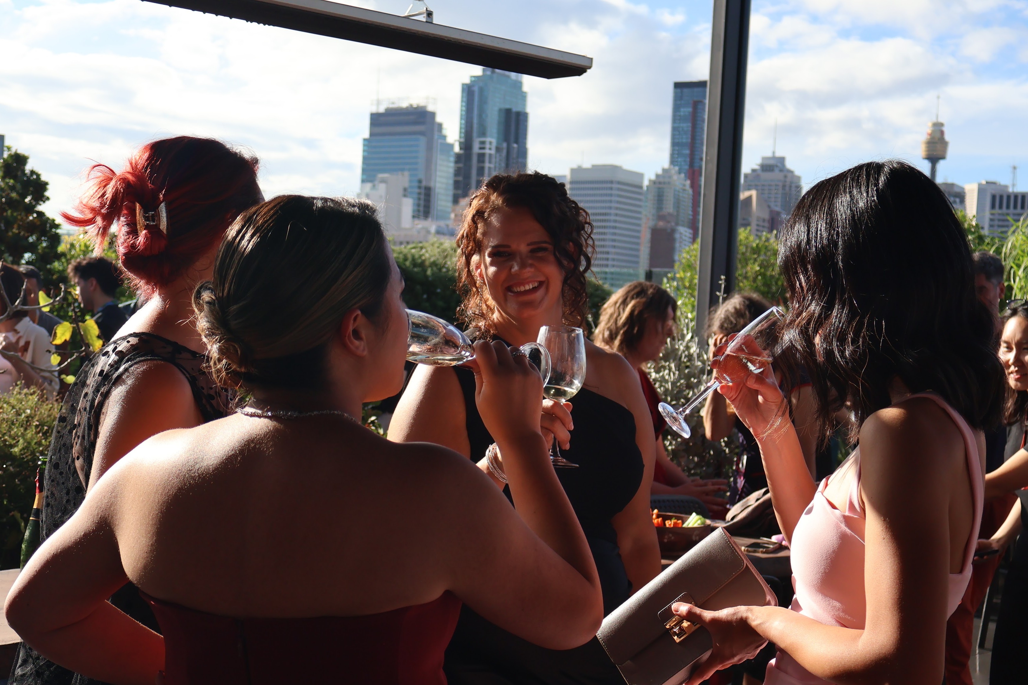 Cheryl laughing with a group of women at an evening event